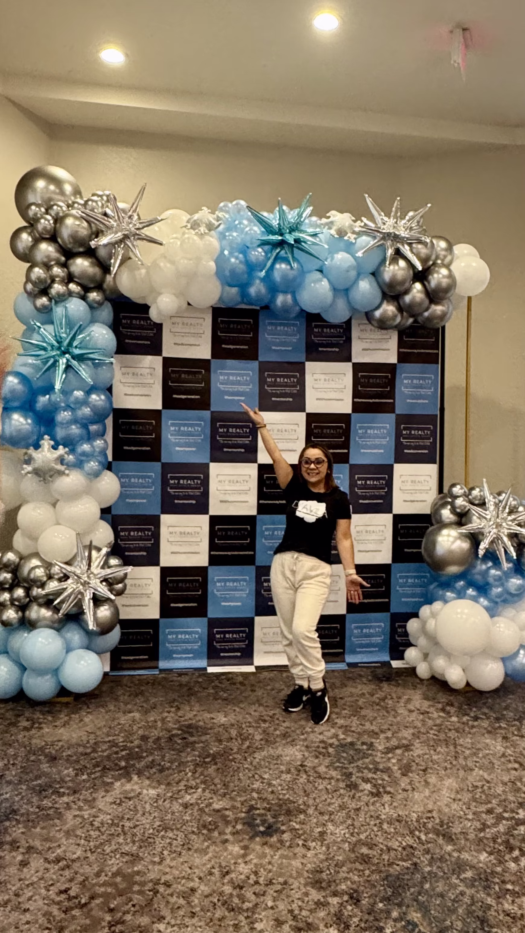 Backdrop corporativo con decoración de globos azul y plateado y logotipo de empresa