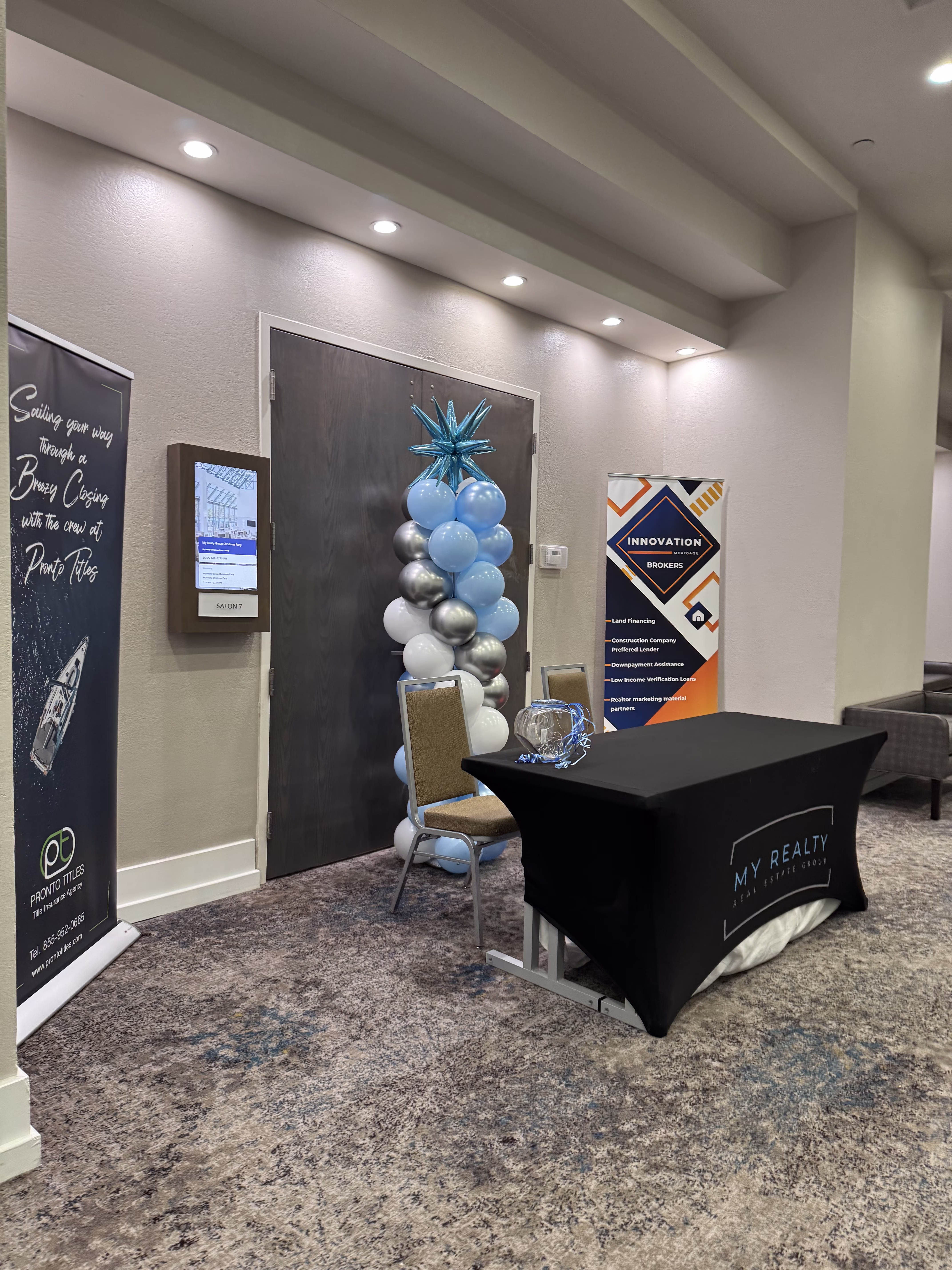 Mesa de registro corporativa con mantel de marca, columna de globos y banners en hotel