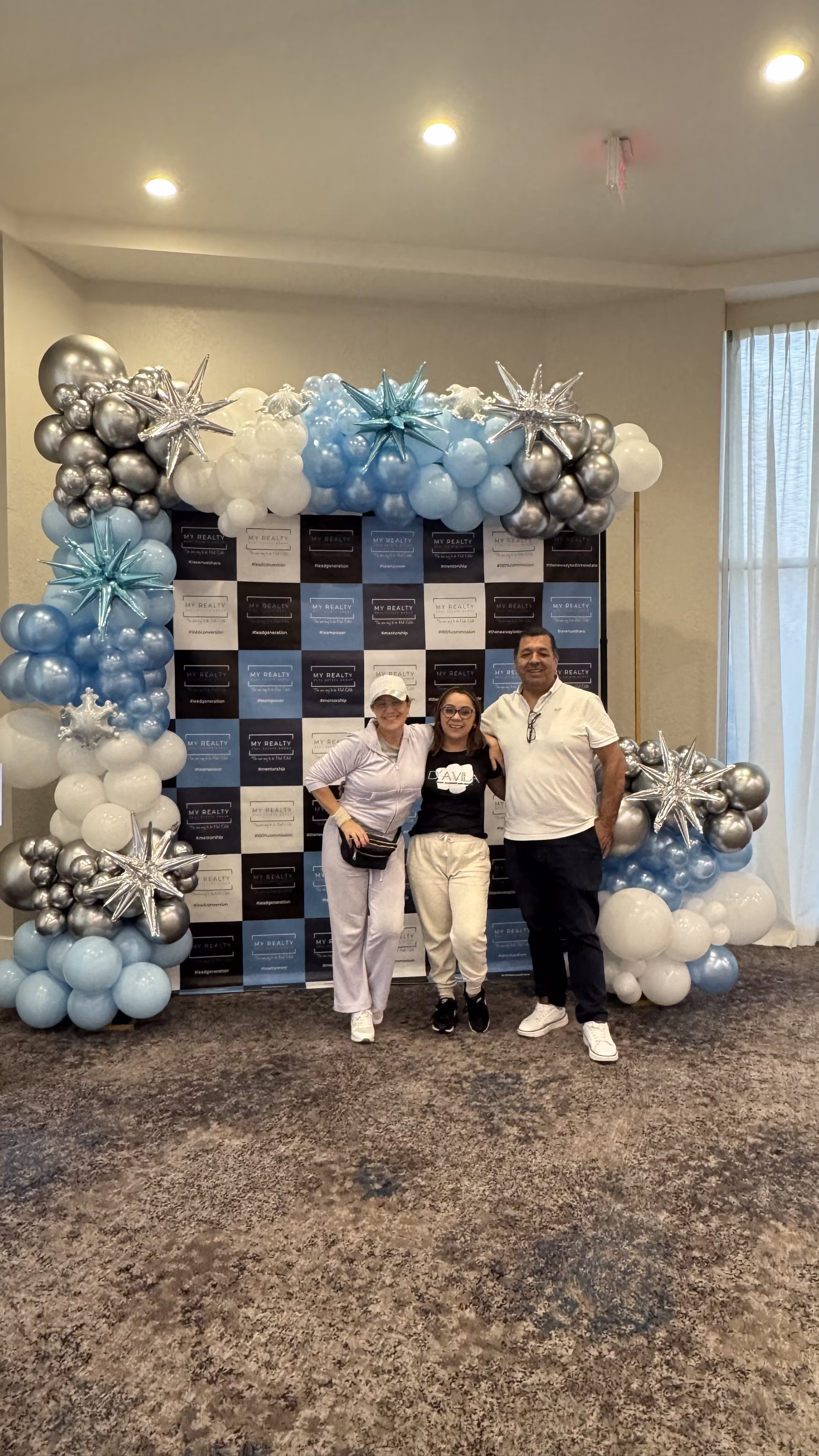Invitados posando en zona de fotos corporativa con backdrop de marca y globos