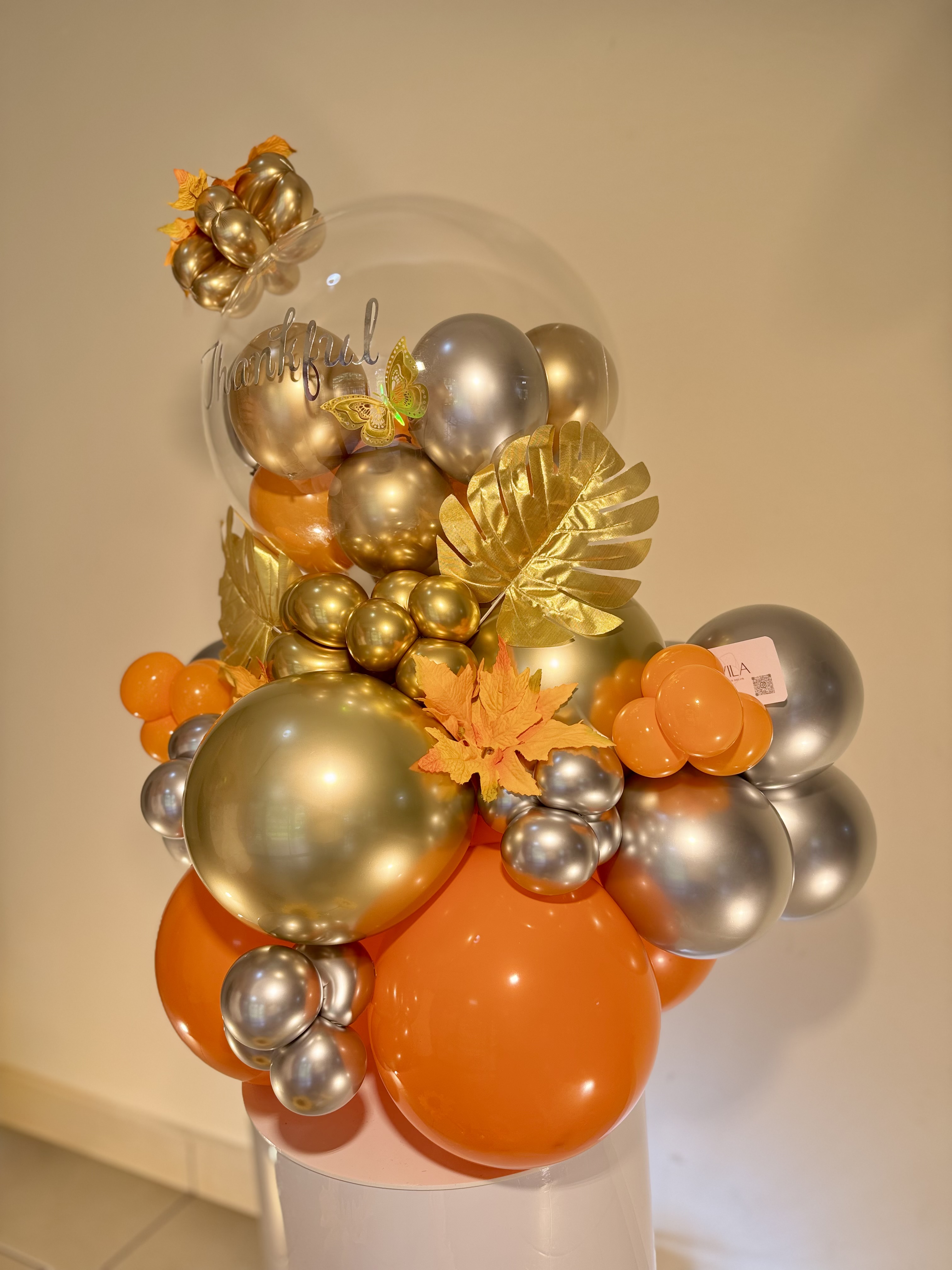 Centro de mesa de globos dorados y naranjas con letrero Thankful